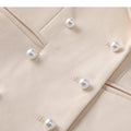 Beige triple-breasted blazer with pearl button detail.