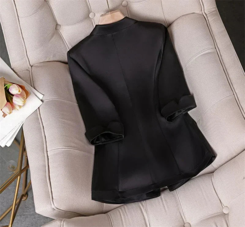 Elegant slim waist black jacket blazer for women with cropped sleeves on a beige tufted chair.