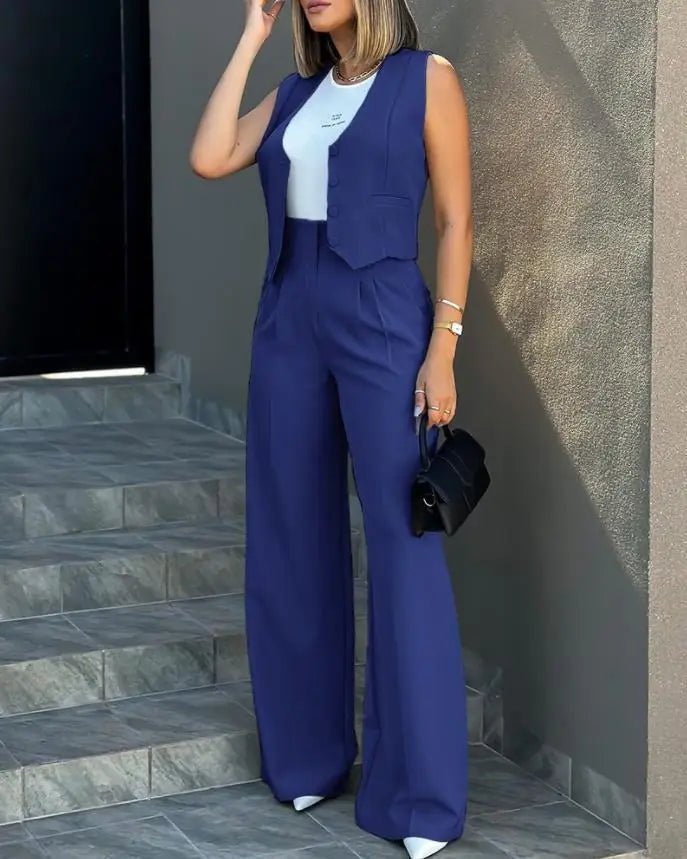 Women's blue blazer pant set with sleeveless notched waistcoat and high-waist straight pants, worn with a white top and black handbag.