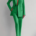 Women's green two piece blazer suit with long sleeves and pencil pants.