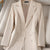 Women's beige long sleeve triple-breasted blazer with notched collar.