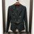 Luxury black double-breasted women's blazer with gold buttons, notched collar, and belted waist